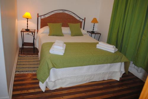 Hostal Petit Verdot في سانتا كروز: غرفة نوم بسرير كبير مع ستائر خضراء