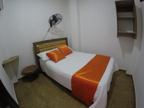 a bedroom with a bed with orange pillows and a fan at Hotel Campestre Maguey in Mangue