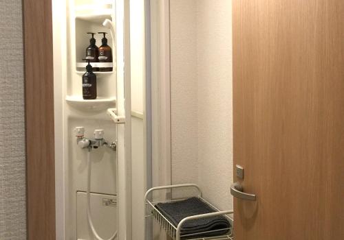 eine Tür, die zu einem kleinen Bad mit einem Kühlschrank führt in der Unterkunft Tsukiji Hostel Wakayama 2 in Wakayama
