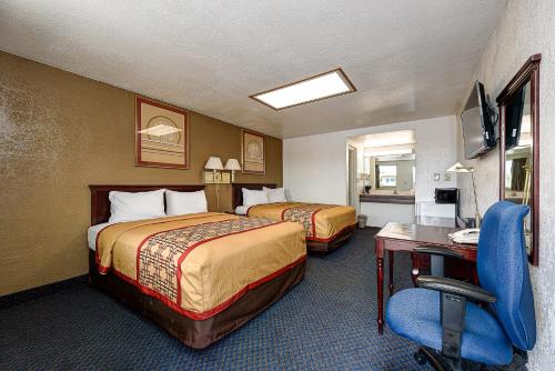 een hotelkamer met 2 bedden en een bureau bij Guest Inn Rogers in Rogers