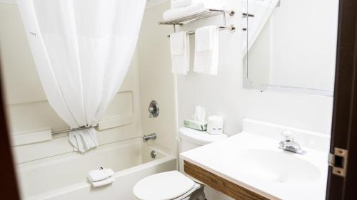 a bathroom with a toilet and a sink and a mirror at Super 8 by Wyndham Groton in Groton