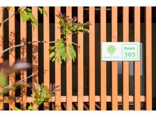 a sign on a wooden fence with a plant at Awajishima Hotel Lodge GREEN COZY in Minamiawaji