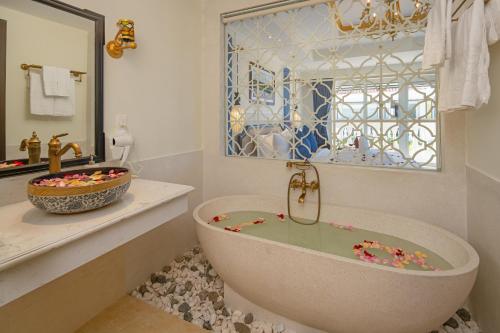ein Badezimmer mit einer Badewanne, einem Waschbecken und einem Spiegel in der Unterkunft Hoi An Blue Sky Boutique Hotel & Spa in Hoi An