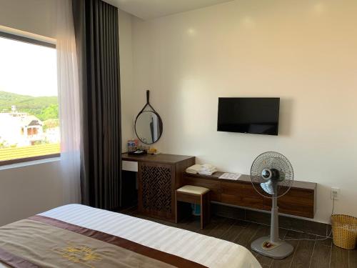 Schlafzimmer mit einem Bett, einem Spiegel und einem Ventilator in der Unterkunft Win Win Hotel - Khách Sạn Hải Phòng in Haiphong