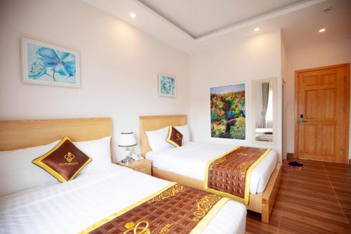 a hotel room with two beds and a door at Golden Bee Hotel in Da Lat