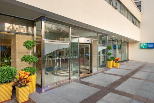 an office building with glass doors and potted plants at Holiday Inn Express Tianjin Airport by IHG in Tianjin