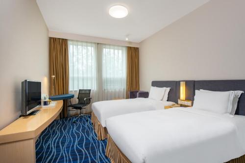 a hotel room with two beds and a television at Holiday Inn Express Tianjin Airport by IHG in Tianjin
