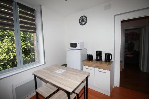 a kitchen with a table and a microwave on a wall at LA MEDINA in La Fère