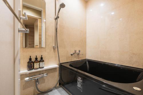 a bathroom with a bath tub and a sink at GRAND BASE Hakatamon in Fukuoka
