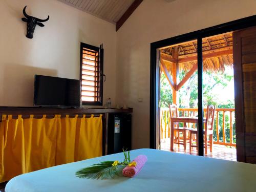 a room with a bed with a television and a table at JJ ET EUPHRASIE Lodge in Nosy Be