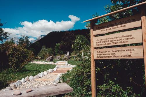 a sign in front of a garden with a trail at Berghotel Rehlegg in Ramsau