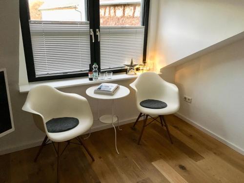 Duas cadeiras e uma mesa num quarto com uma janela em Milchhaus Zimmer - Tiny House em Balingen