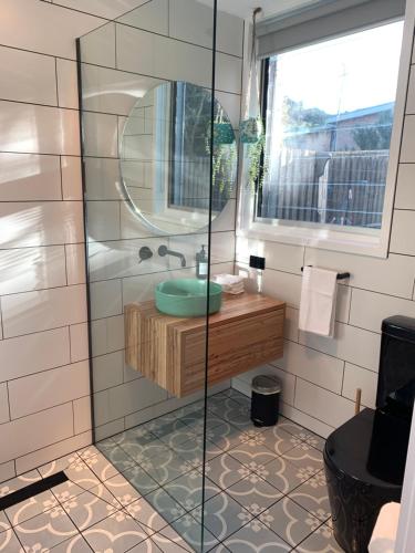 ein Bad mit einer Dusche, einem Waschbecken und einem Spiegel in der Unterkunft Sorrento Back Beach Apartment in Sorrento