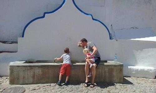 a man and two children sitting next to a wall at Casas De Romaria in Brotas