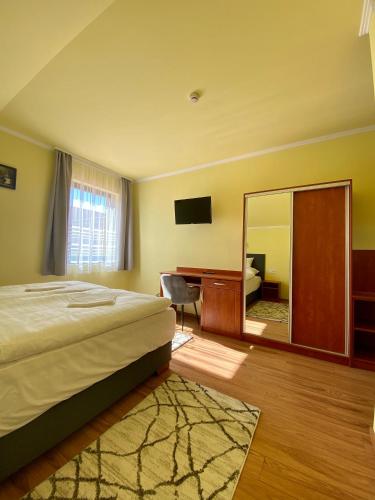 a bedroom with a bed and a desk and a mirror at Rábensteiner Panzió in Fertőd