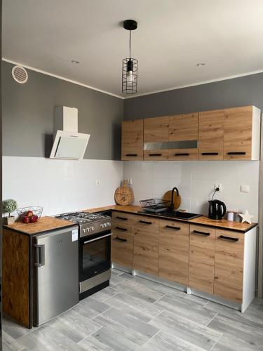 eine Küche mit Holzschränken und Küchengeräten aus Edelstahl in der Unterkunft Apartamenty ToTuGdynia 6 in Gdynia