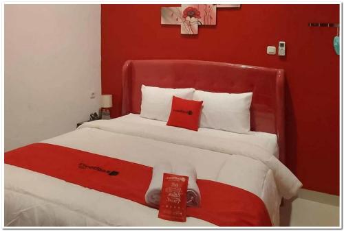 a red and white bed with two red pillows on it at RedDoorz @ Sindangbarang Bogor in Bogor