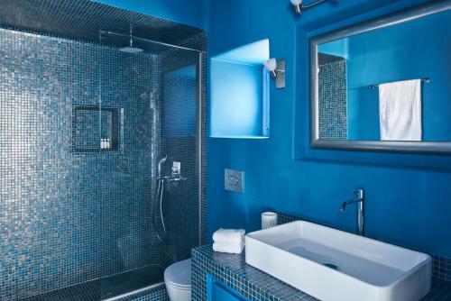 y baño azul con lavabo y ducha. en Villa Rodakes, en Vourvoúlos