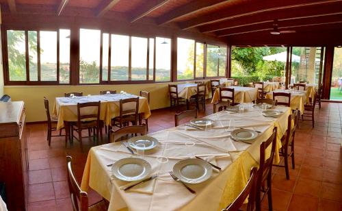 a dining room with tables and chairs and windows at Chiaraluce Country House in Massignano
