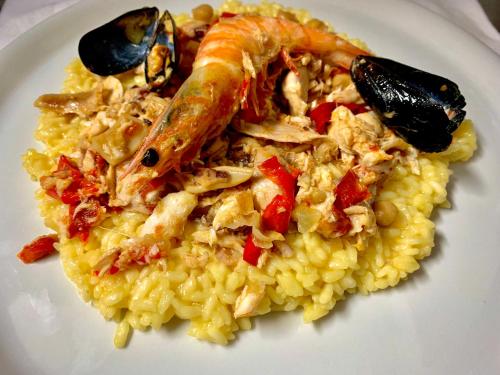 a white plate of food with seafood and rice at Chiaraluce Country House in Massignano