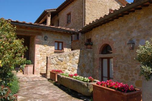 a stone building with flowers in front of it at Locanda Vesuna Hotel Countryhouse in Pienza