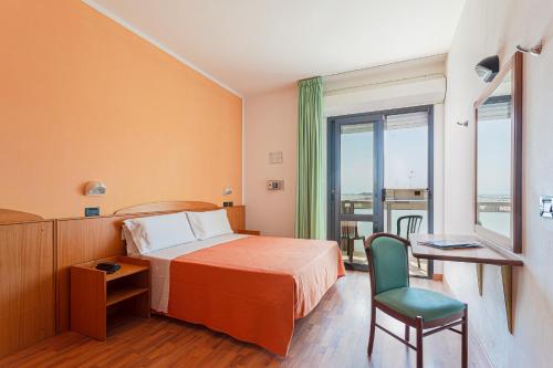 una camera d'albergo con un letto, una sedia e una finestra di Little Hotel a Cesenatico