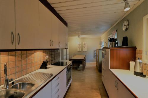 una cocina con armarios blancos y una mesa en el fondo en RIBO Apartment Aurora, en Kiruna