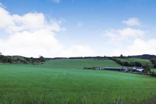 a large green field with a farm in the background at Borthwick Castle View in North Middleton