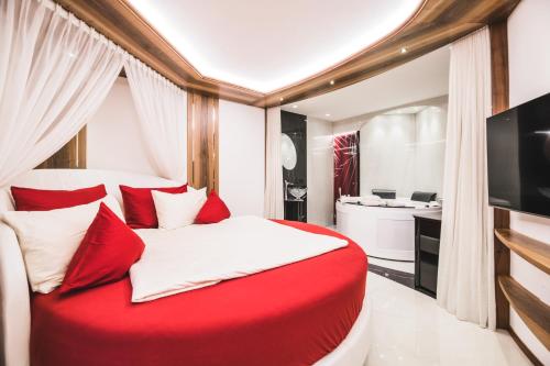 a bedroom with a red and white bed and a bathroom at Apartments Villa Venezia Luxury in Ortisei