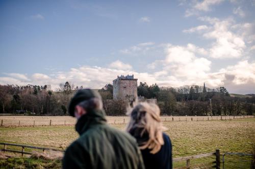 a man and woman walking in front of a castle at Borthwick Castle View in North Middleton