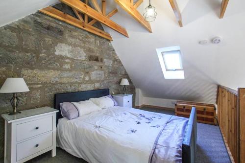 a bedroom with a bed and a stone wall at Borthwick Castle View in North Middleton