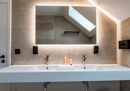 a bathroom with two sinks and a mirror at XXV House - 12 personnes in Héron