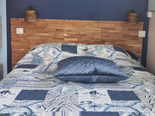 a bed with a blue and white quilt with a pillow at Envolée Marine pour 3 pers - Berck-Plage - 250m plage et commerces in Berck-sur-Mer