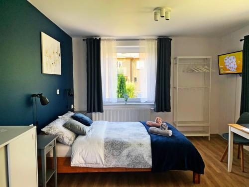 ein Schlafzimmer mit einem Bett mit blauen Wänden und einem Fenster in der Unterkunft Apartamenty Nad Rzeką in Polanica-Zdrój