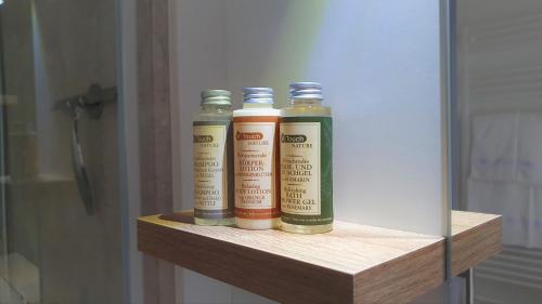 three bottles sitting on a wooden shelf in a bathroom at PB Ferienwohnungen - FeWo 5 - Stilvoll eingerichtetes Studio im Herzen Senftenbergs in Senftenberg