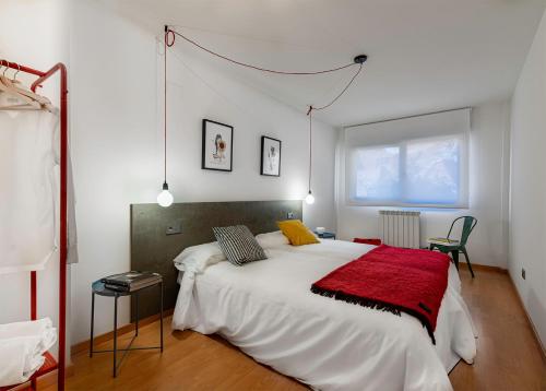 a bedroom with a large white bed with a red blanket at Apartamentos Turísticos Rioja y Camino in Huércanos