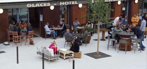 een groep mensen die aan tafels buiten een gebouw zitten bij Hôtel Terminus in Luz-Saint-Sauveur