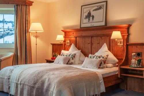 1 dormitorio con cama con cabecero de madera y almohadas en Harmony Hotel Sonnschein, en Niederau