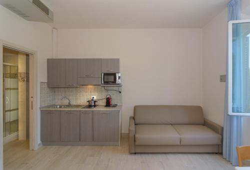 a kitchen with a couch and a sink and a microwave at Hotel Sogno in Viareggio