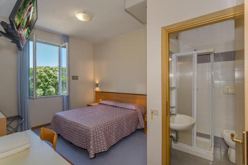 a bedroom with a bed and a bathroom with a sink at Hotel Sogno in Viareggio