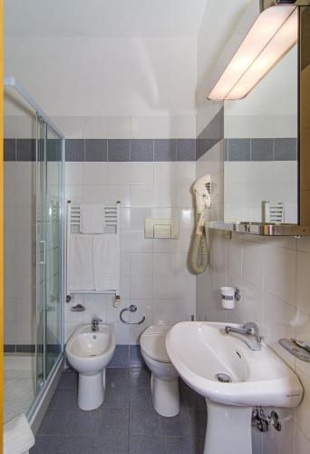 a bathroom with two toilets and a sink and a shower at Hotel Sogno in Viareggio