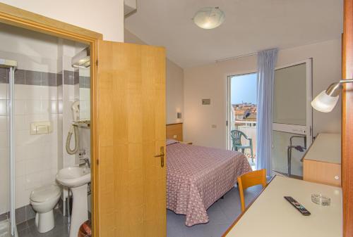 a bedroom with a bed and a bathroom with a sink at Hotel Sogno in Viareggio