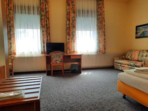 Traube Hotel Oeffingen في فيلباخ: غرفة معيشة مع أريكة ومكتب ونوافذ