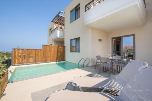 a villa with a swimming pool and a table and chairs at Stefan Village Hotel in Agia Marina Nea Kydonias