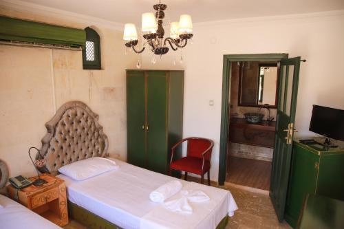 a bedroom with a bed and a chair and a television at Narlı Ev Butik Otel in Sanlıurfa