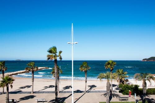 a cross on a beach with palm trees and the ocean at Hôtel Bel Azur in Six-Fours-les-Plages