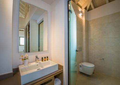 a bathroom with a sink and a toilet and a mirror at Stefan Village Hotel in Agia Marina Nea Kydonias