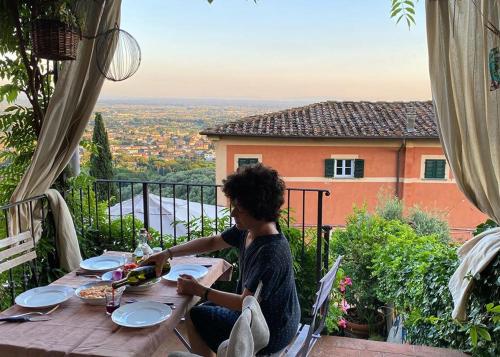 a woman sitting at a table on a balcony at Residenza Buggiano Antica B&B - Charme Apartment in Tuscany in Borgo a Buggiano