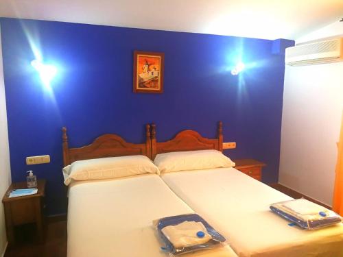 a bedroom with a bed with a blue wall at Hostal Restaurante Ego's in Campo de Criptana