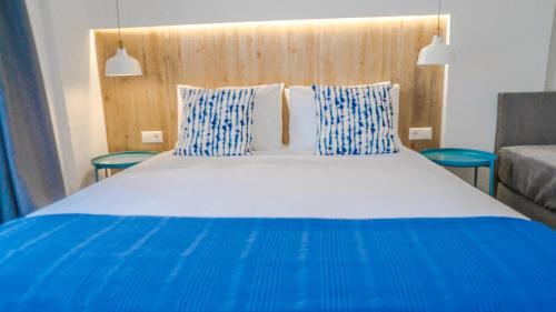 een groot blauw en wit bed met blauwe en witte kussens bij Anfi Suites in Gouves